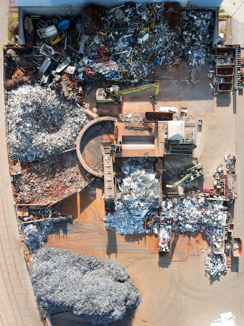 Vue plongeante sur une installation industrielle de tri et traitement des déchets, avec des piles de matériaux recyclables et une trieuse de déchets en activité. d'une machine de tri des déchets.